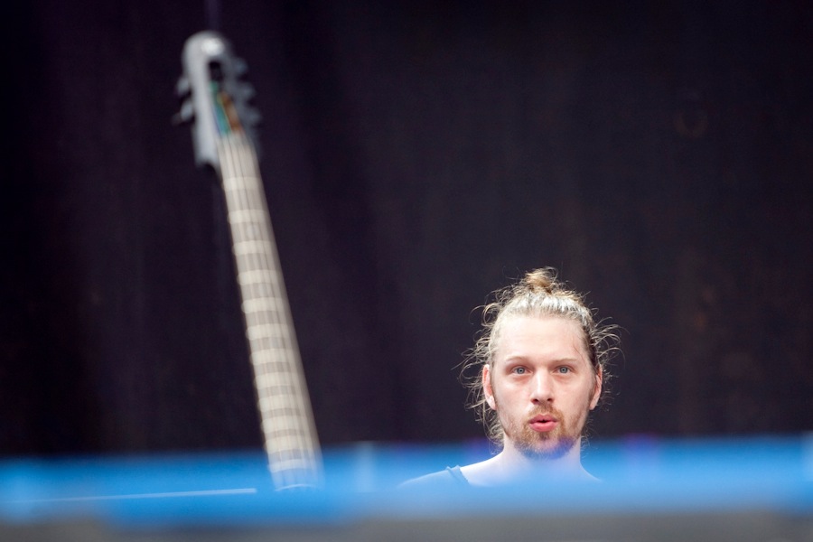 Sarth Calhoun performing at Lollapalooza, a bass headstock in the foreground.