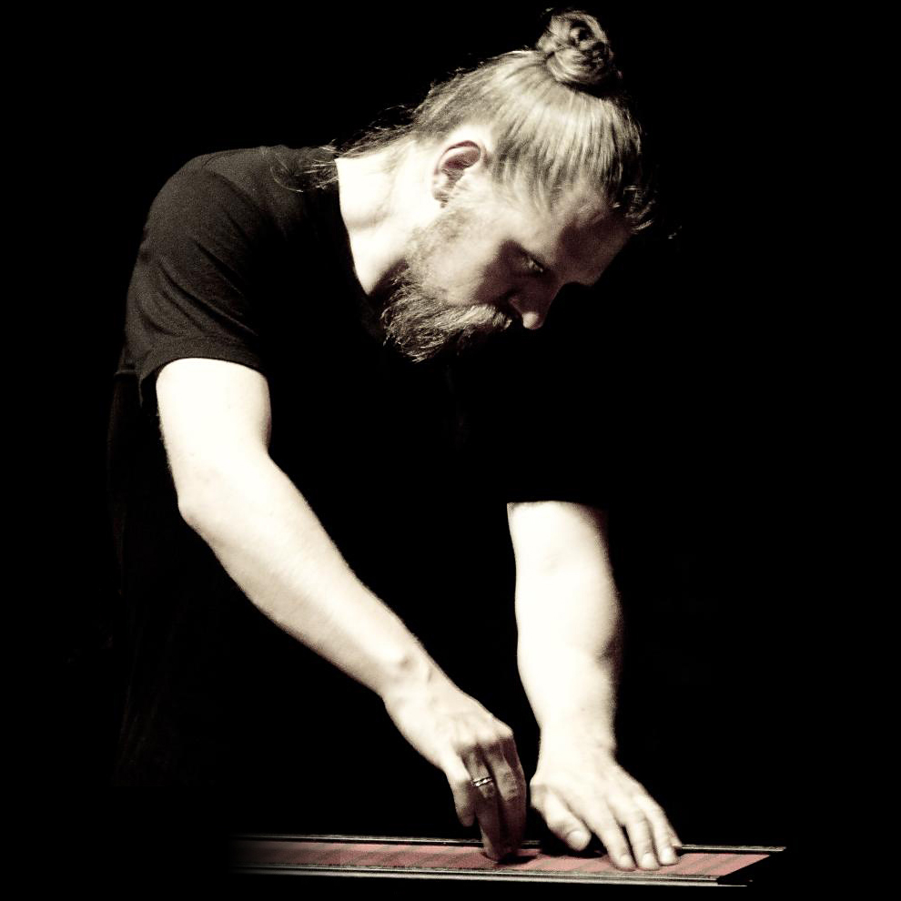 Sarth Calhoun bent over a Continuum Fingerboard, black and white.